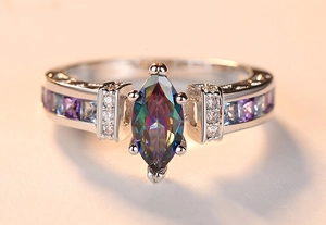 Macro detail of silver ring with colorful marquise-cut gemstone and side crystals