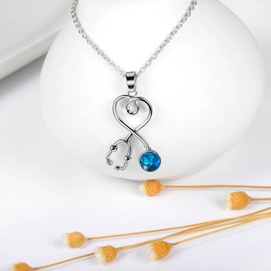 Detalle del collar con colgante de estetoscopio de corazón y cristal azul brillante
