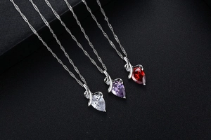 Three teardrop crystal necklaces in purple red and white on black textured fabric