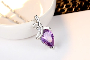 Macro view of purple teardrop gemstone pendant with silver streamlined elegant design