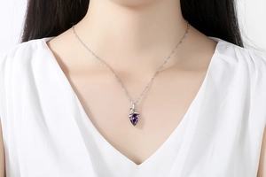 Detail of a purple teardrop gemstone pendant necklace worn on a silver chain
