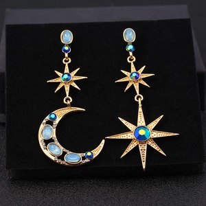 Detailed close-up of Bohemian star and moon earrings with blue opal-like gemstones