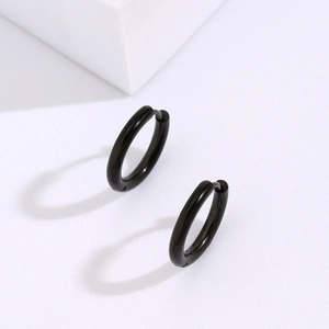 Detail view of glossy black stainless steel huggie hoop earrings on a white stand