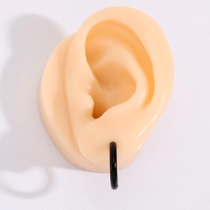 Detail of minimalist black stainless steel hoop earring worn on an ear model
