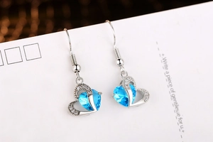Macro shot of silver-plated heart earrings with blue cubic zirconia on white card