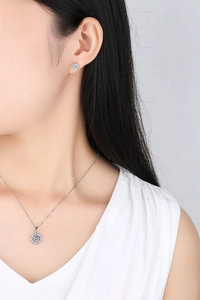 Close-up of elegant halo pendant necklace and stud earrings set on a female model
