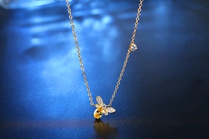 Détail macro du collier abeille dorée avec pierre jaune et ailes pavées de zircons