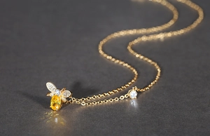 Vue détaillée d'un collier pendentif abeille avec une pierre jaune et diamants incrustés