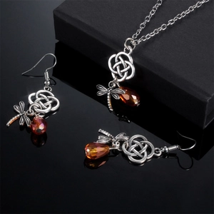 Silbernes Libellen-Schmuckset mit bernsteinfarbenen Perlen auf schwarzem Hintergrund