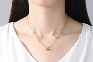Détail du collier pendentif abeille dorée avec cristal jaune et zircon sur le cou