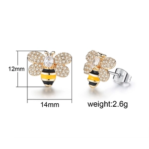 Détail macro de boucles d'oreilles abeille dorées avec ailes en zircon étincelantes