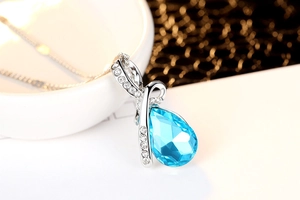 Macro shot of blue teardrop crystal pendant with zircon accents on silver chain