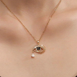 Gros plan du collier œil maléfique en or avec zircons et pendentif goutte sur peau
