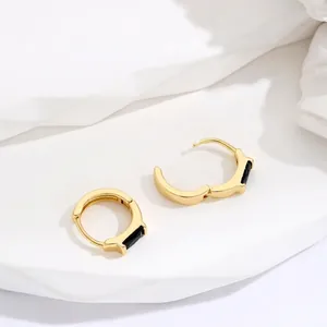 Minimalist gold hoop earrings with rectangular black inlay shown on white stone pedestal