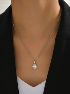 Gros plan du collier élégant avec pendentif en zircon goutte d'eau porté sur un blazer noir