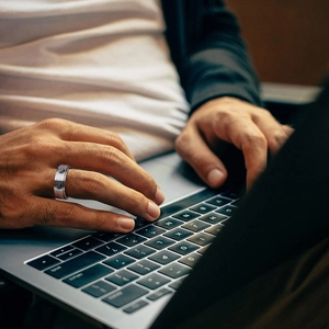 Men's 8mm stainless steel spinner ring with Tai Chi pattern shown on hand while typing