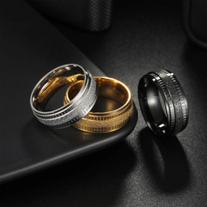 Three-piece men's steel ring set in silver, gold, and black with a matte frosted finish