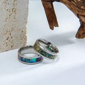 Men's titanium steel rings with iridescent abalone shell inlay on natural wood and stone