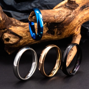 Bagues minimalistes en acier poli, finitions bleu, argent, or et noir sur bois sombre