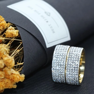 Detailansicht von gold- und weißfarbenen breiten Ringen mit fünfreihiger Zirkonia-Pflasterung