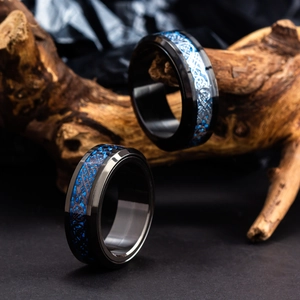 Gros plan de bagues en acier titane noir avec dragon celtique bleu sur branche de bois