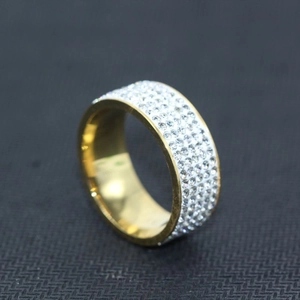 Makro-Nahaufnahme des goldenen breiten Ringes mit vier Reihen funkelnder Kristalle