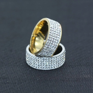 Detail von Gold- und Silber-Cuban-Ringen mit weißen Kristallen auf grauer Oberfläche