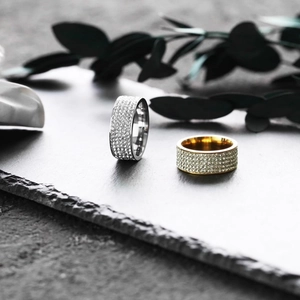 Cuban Iced-Out Ringe in Gold und Silber mit Pave-Zirkon auf einem steinernen Hintergrund