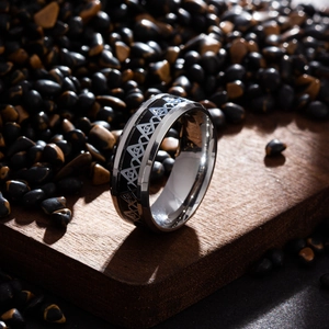 Macro shot of polished stainless steel Freemason ring with black Masonic symbols on wood