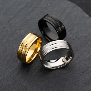 Detailed view of matte black, gold, and silver titanium rings with double grooved lines