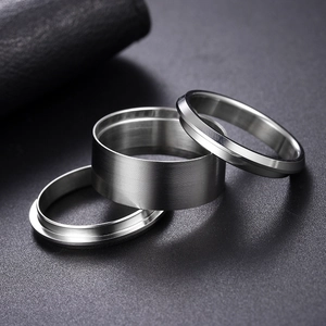 Macro shot of three minimalist stainless steel DIY rings with brushed metal texture finishes