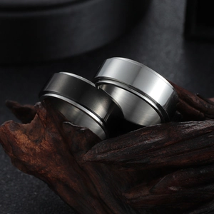 Minimalist spinning titanium steel rings in black and silver on rustic wood background