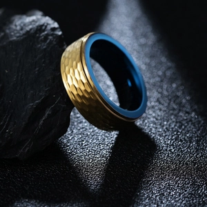 Bague en tungstène martelé doré pour homme avec intérieur bleu sur fond rocheux