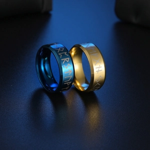 Nahaufnahme von blauen und goldenen Edelstahlringen mit gravierten Wikinger-Runen