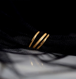 Macro shot of three golden stainless steel rings with polished and frosted textures on black mesh
