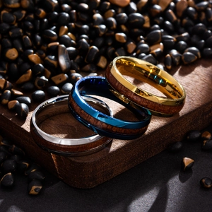Detailed view of titanium steel rings with wood inlay in gold, blue, and silver finishes