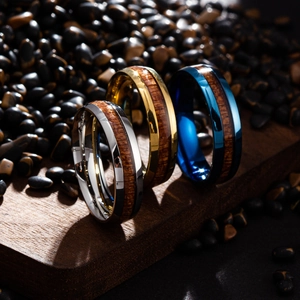 Detailed view of polished titanium rings with wood inlays in silver, gold, and blue colors