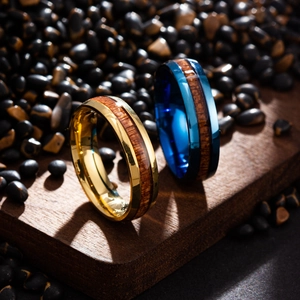 Macro shot of gold and blue titanium rings with natural wood inlay on pebble background