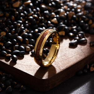 Macro shot of polished gold titanium ring with dark wood inlay on a wooden pedestal