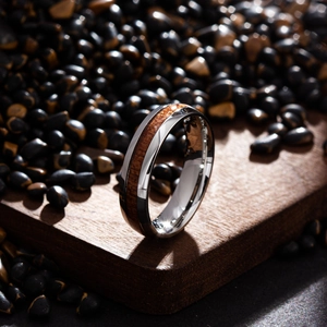 Macro view of a polished titanium steel ring with brown wood inlay on a stony display