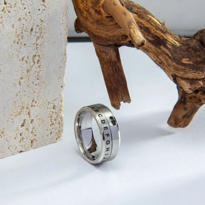 Close-up of rotating titanium steel ring with engraved black letters on silver band