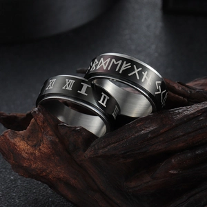 Macro shot of rotatable stainless steel rings with Roman numerals and Viking runes on wood