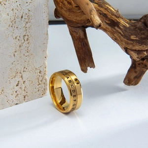 Detail shot of golden spinning spinner ring with Roman numerals on natural stone