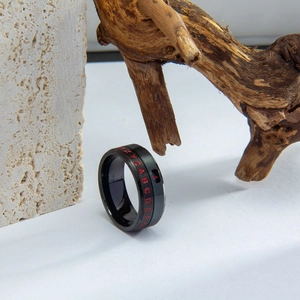 Macro detail of rotating black titanium ring with red engraved letters on stone texture