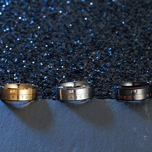 Rotating stainless steel alphabet rings in gold, silver, and black finish on stone