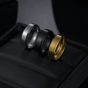 Close-up of 6mm stainless steel rings in silver, black and gold on black leather