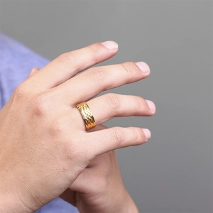 Detail showing the 3D hammered texture and golden metallic finish of the men's steel ring