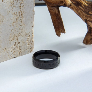 Close-up of vintage black titanium steel ring with Nordic Viking rune engravings on stone