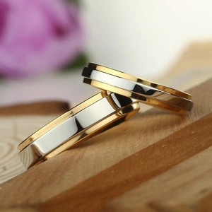 Macro detail of two-tone tungsten couple rings with stepped gold and silver layering