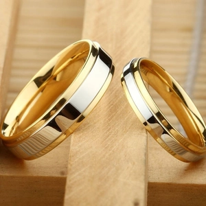 Close-up of gold and silver tungsten couple rings set on a premium wooden display
